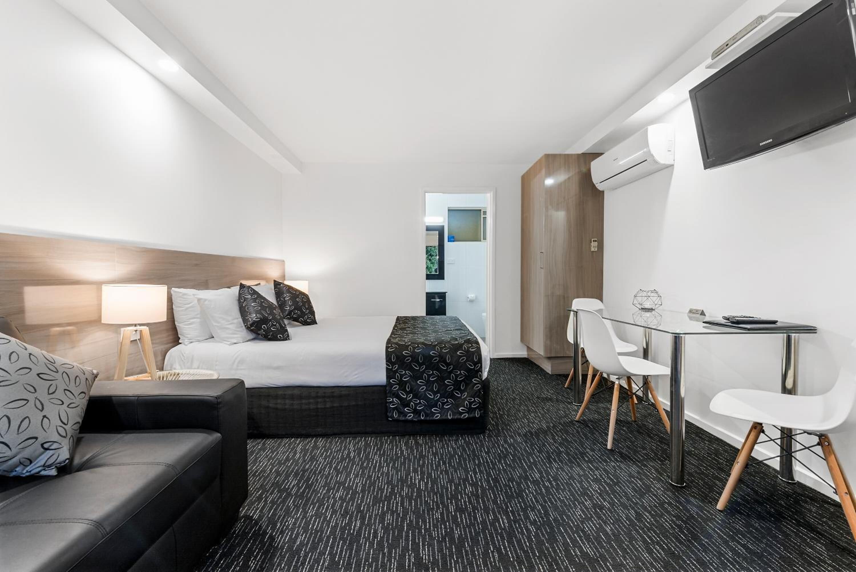 Une chambre d’hôtel équipée d’un lit, d’un bureau, d’une chaise, d’un canapé et d’une télévision.