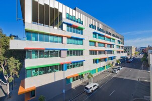 A multi-story building with large windows and a parking lot.
