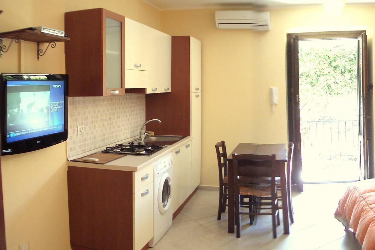 Una camera d'albergo compatta con angolo cottura, zona pranzo e un letto.