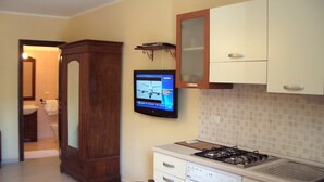 A kitchen with a stove, washing machine, and a television mounted on the wall. - Casa Giuditta Appartamenti (Palermo)
