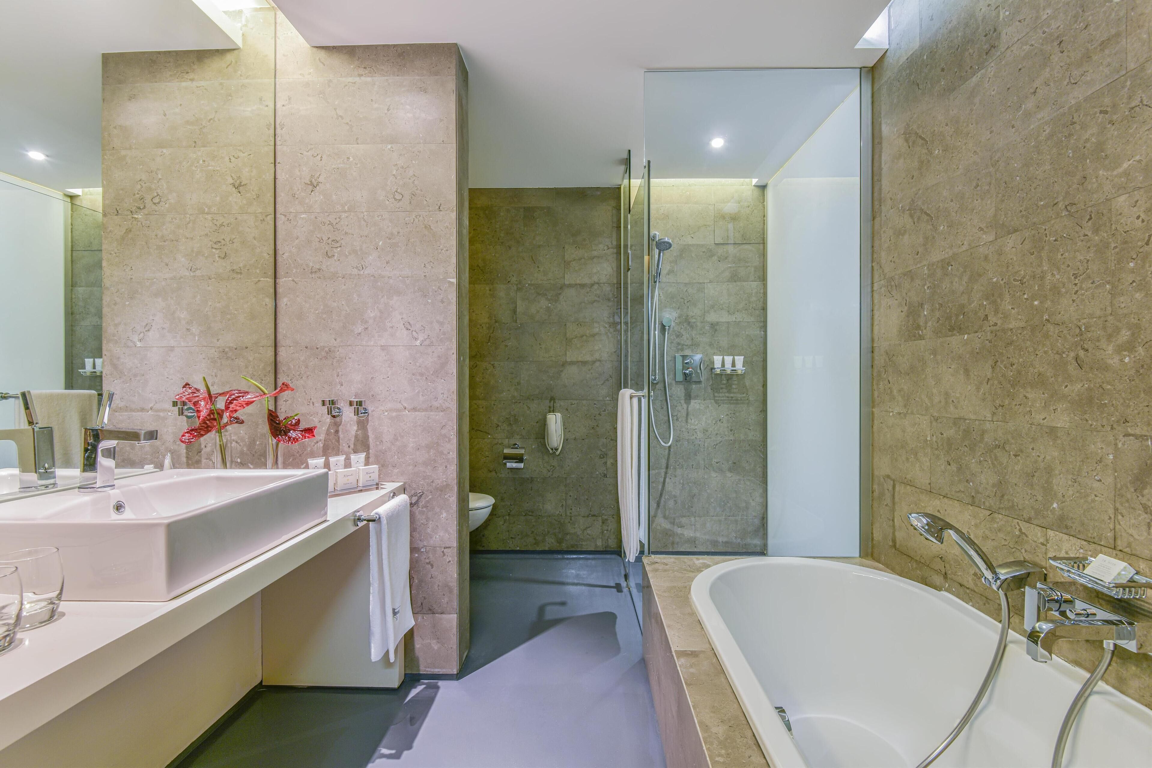 Un baño moderno con una bañera grande, una zona de ducha separada y un tocador con lavamanos y espejo.