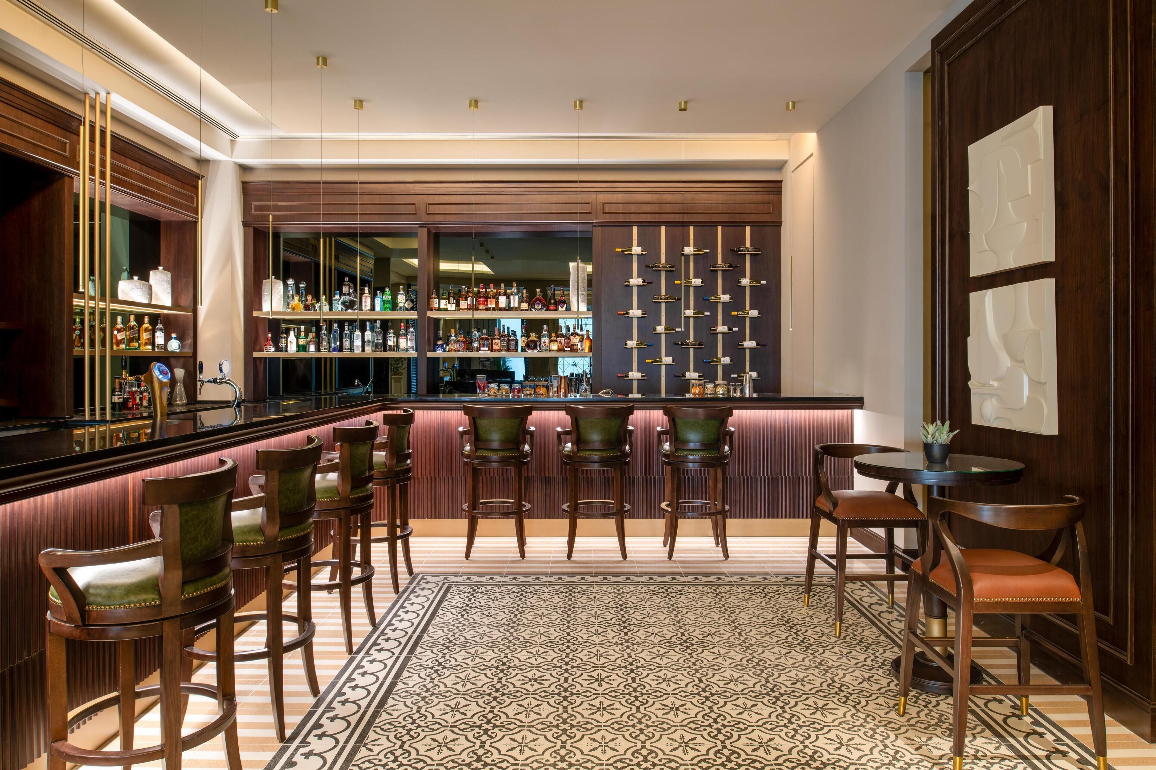 Una zona de bar con taburetes de madera, un tapete estampado y una barra bien surtida.