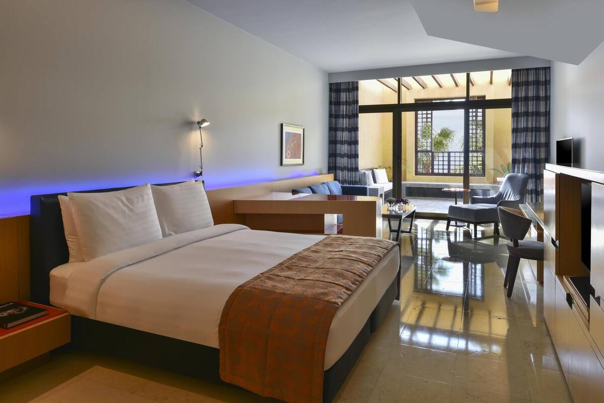 A hotel room with a large bed, a desk, a chair, and a TV.