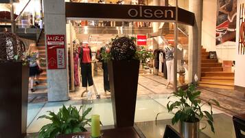 Un restaurante con mesa y sillas de vidrio, una planta en maceta y un cartel de 'Olsen' al fondo.