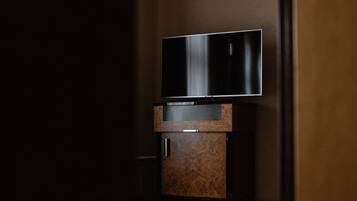 Ein Zimmer mit einem an einer Holzkabine montierten Flachbildfernseher, einem gemusterten Teppich auf dem Boden und einer teilweise geöffneten Tür.