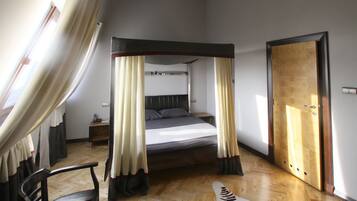 Un dormitorio con una cama con dosel, una puerta de madera y una ventana con cortinas.
