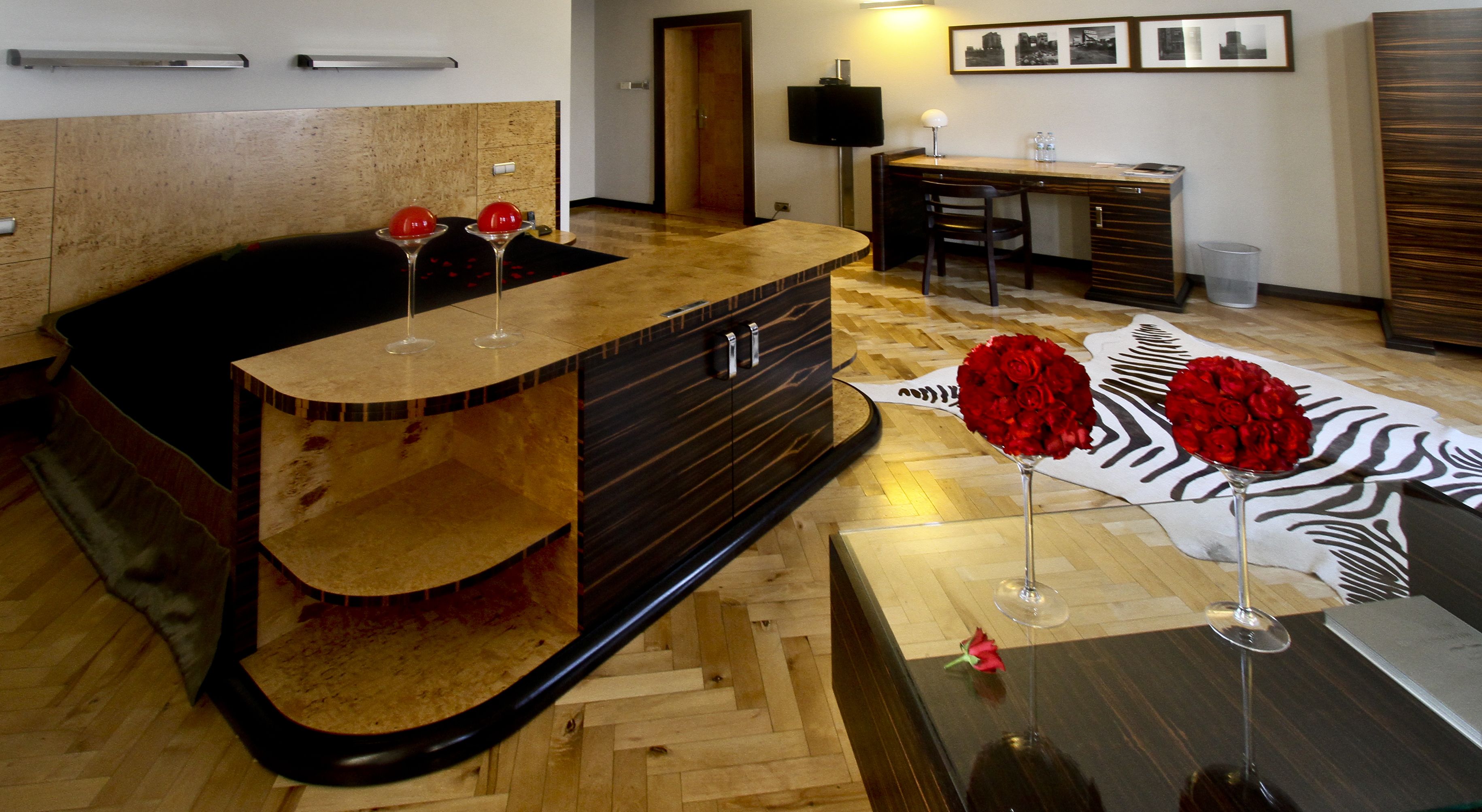 Habitación de hotel moderna con una bañera de madera, un escritorio con silla, un televisor de pantalla plana y una alfombra con estampado de cebra.