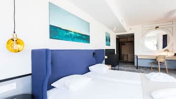 Habitación de hotel con una cama grande, un escritorio, una silla, un espejo y obras de arte en las paredes.