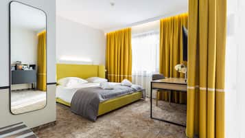 Ein Hotelzimmer mit einem Bett, einem Schreibtisch, einem Stuhl, einem Spiegel und Vorhängen.