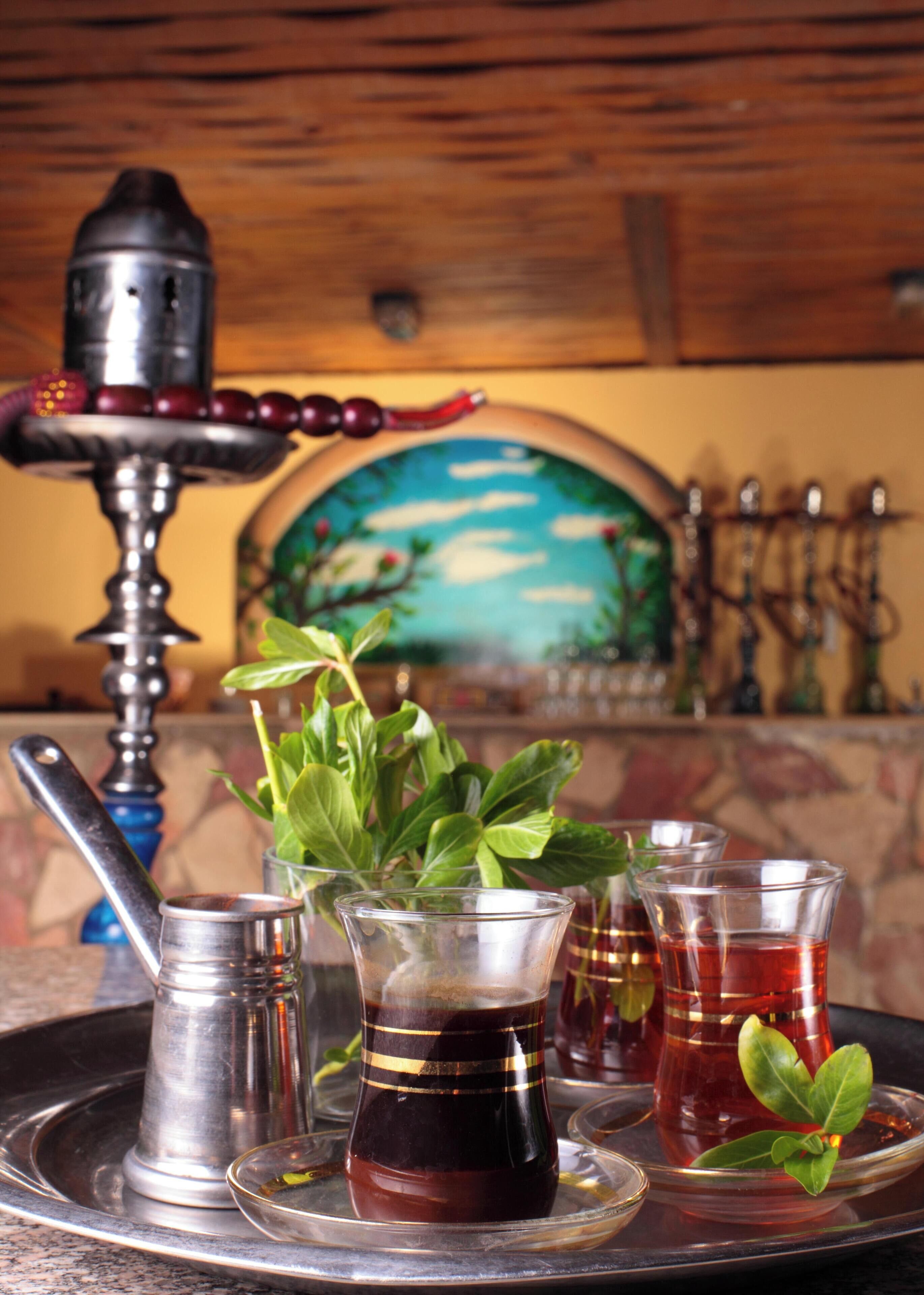 A hookah setup with a hookah, glass, and tea glasses on a tray.
