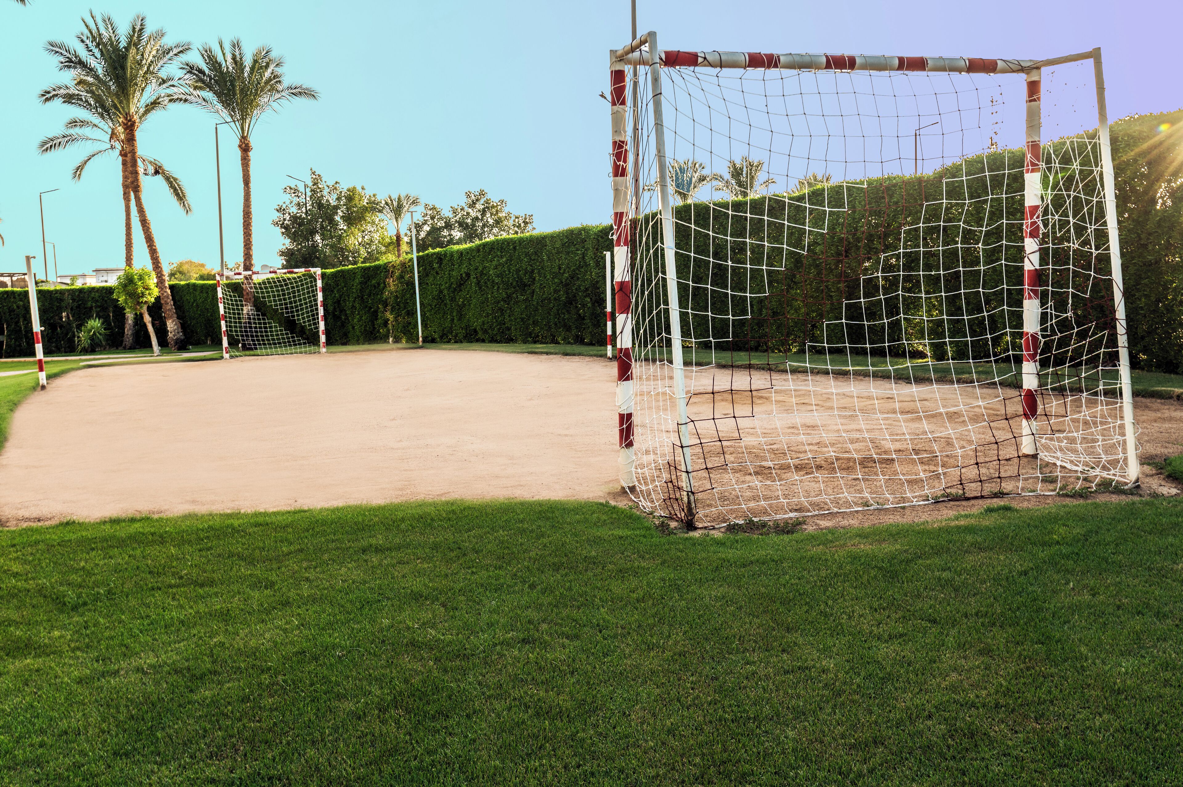 A soccer goal in a well-maintained field with a clear sky.