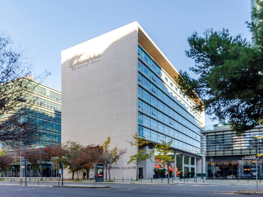 A modern hotel with a prominent white facade and large glass windows.