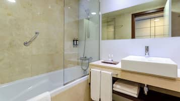 A modern bathroom with a glass-enclosed shower, a white bathtub, and a sink with a mirror above it.