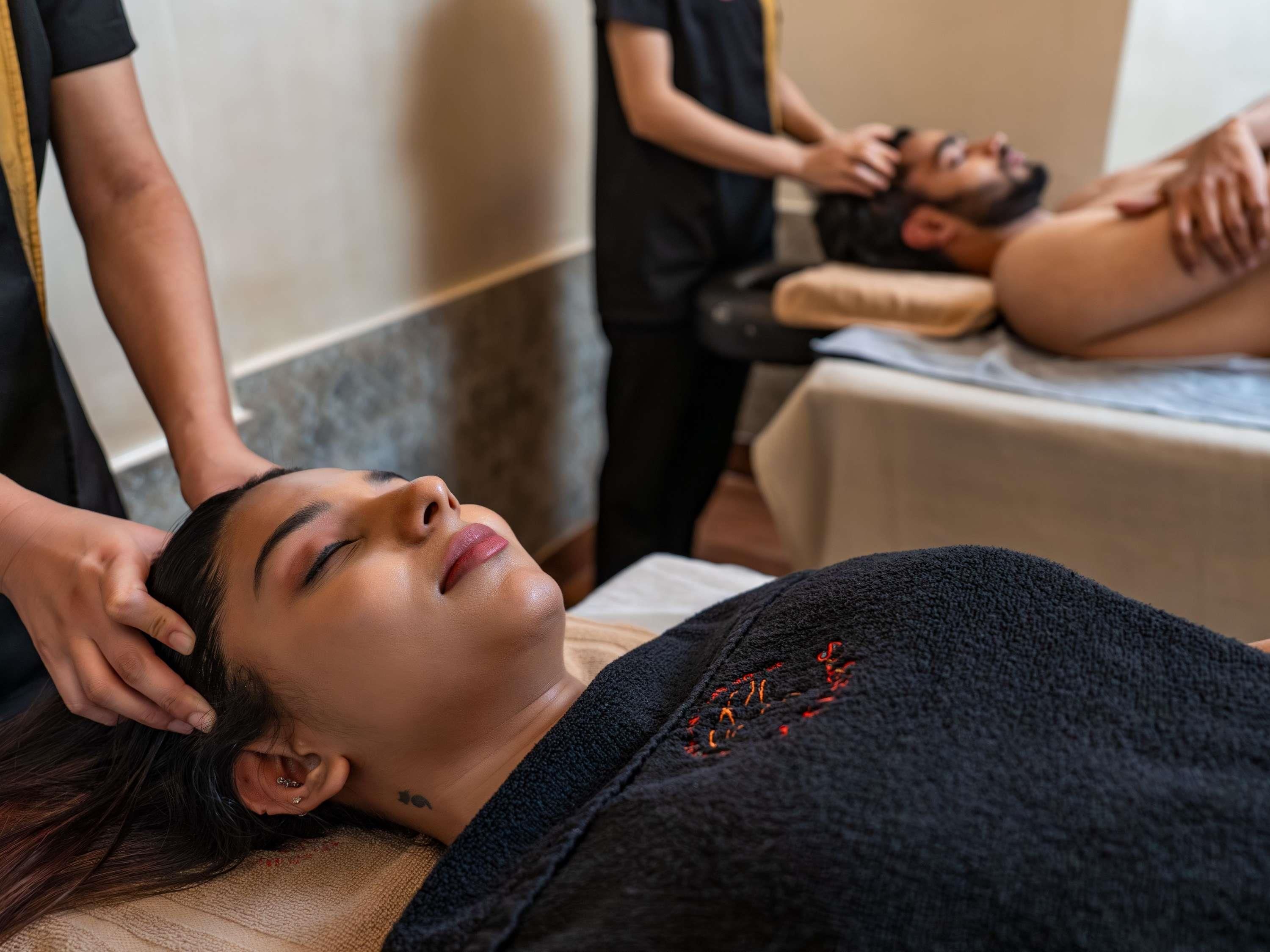A person receiving a massage in a room with a massage table and a massage therapist.