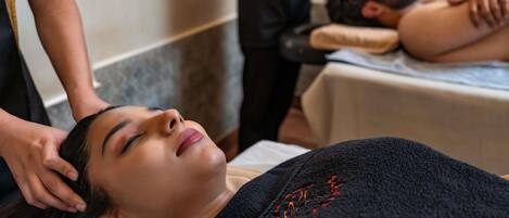 A person receiving a massage in a room with a massage table and a massage therapist.