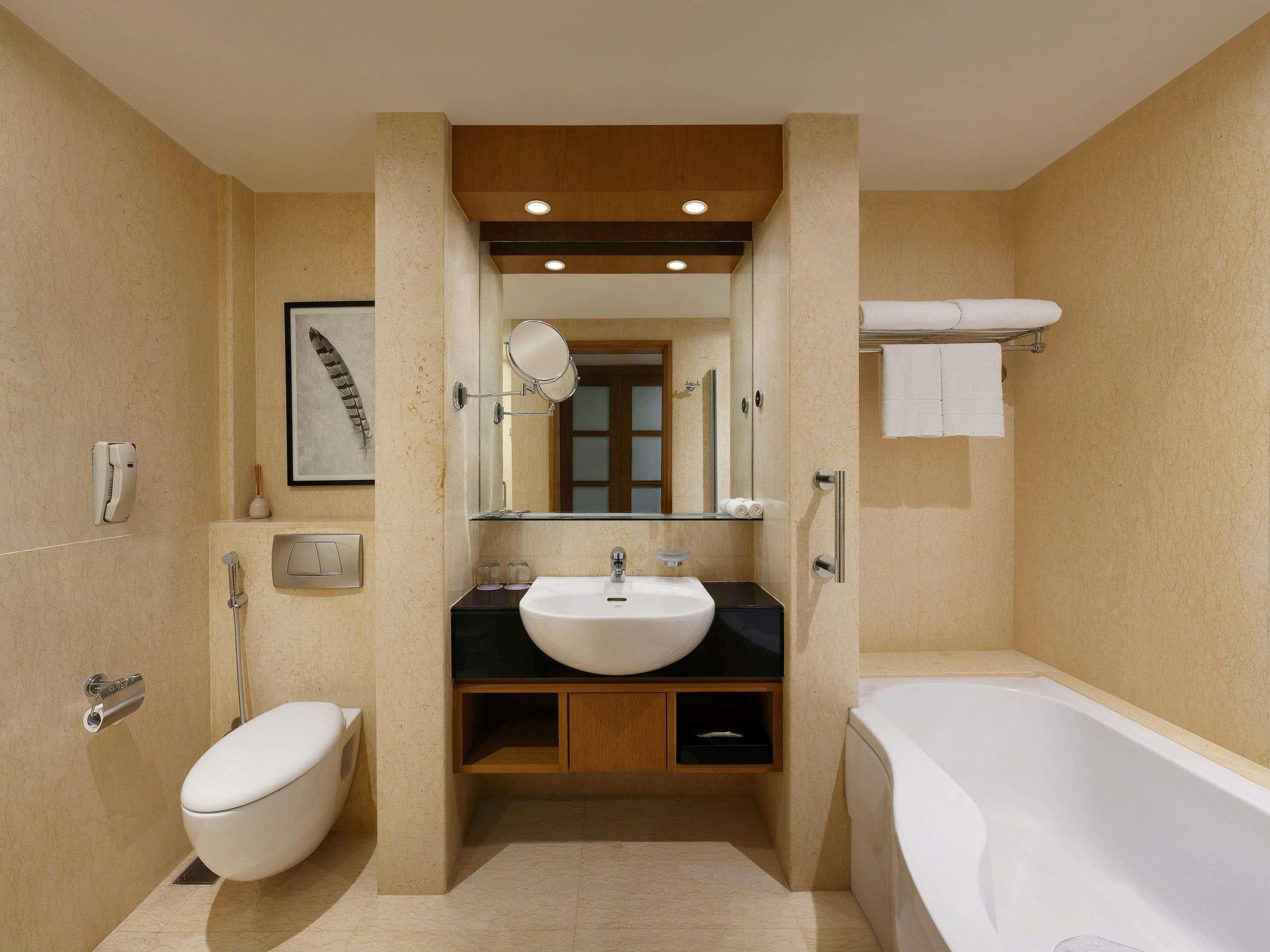 A modern bathroom with a bathtub, toilet, sink, and a mirror.