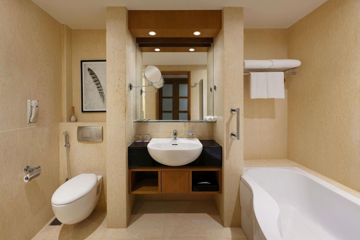 Un baño moderno con bañera, inodoro, lavabo y espejo.