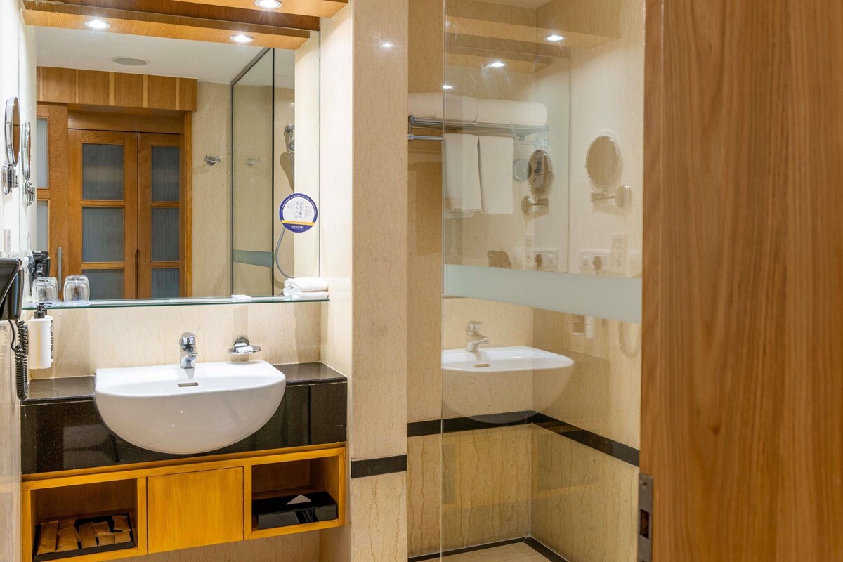 A modern bathroom with a large mirror, two sinks, and a glass shower enclosure.
