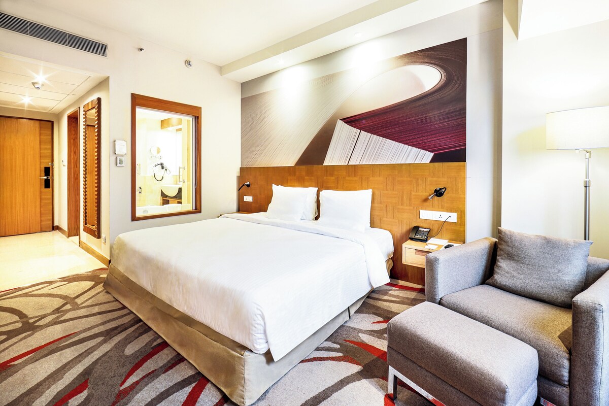 Een hotelkamer met een groot bed, een bureau, een stoel en een aan de muur bevestigd telefoon.