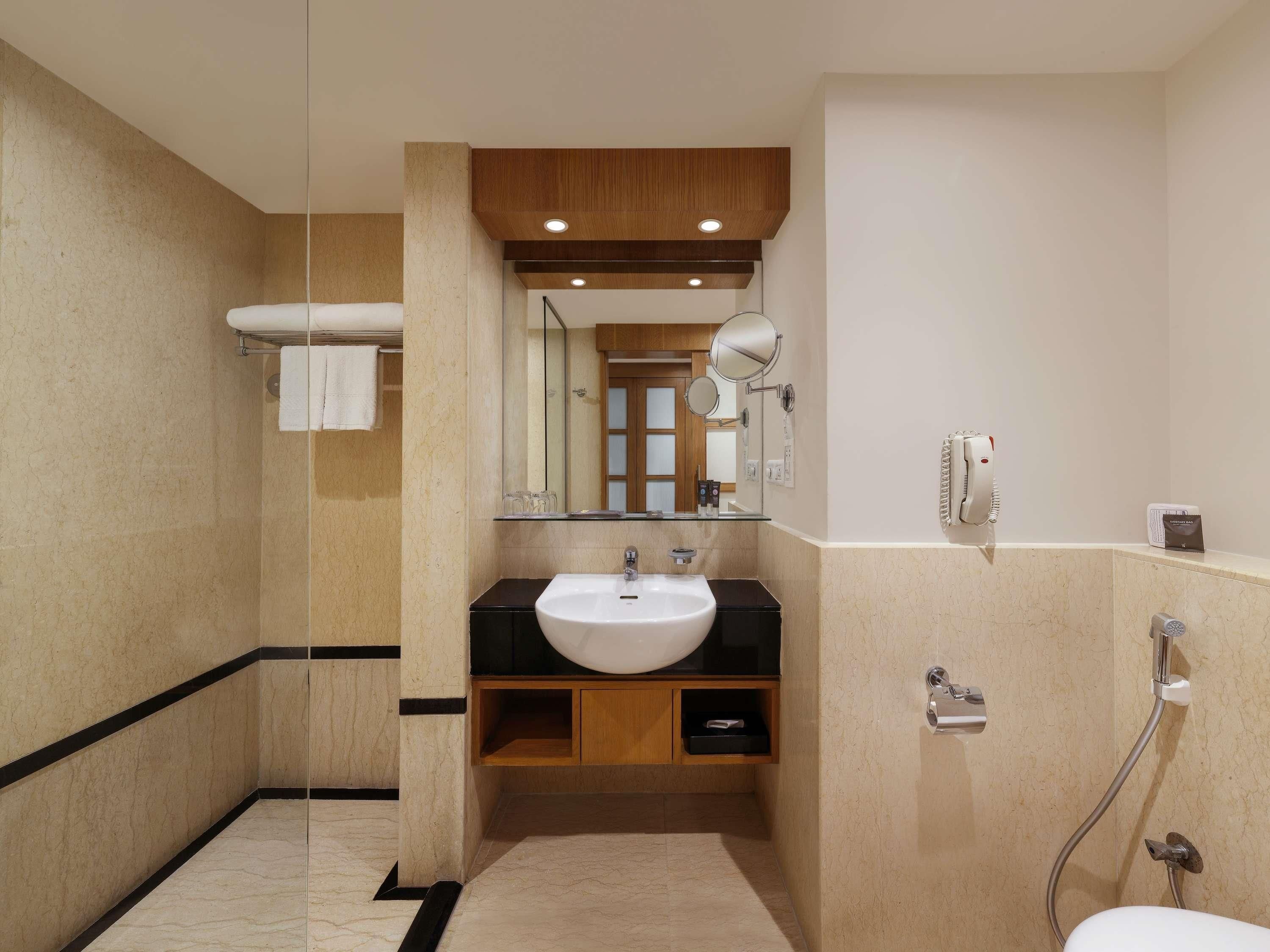 A modern bathroom with a glass shower enclosure, a white sink, and a mirror above the vanity.