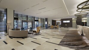 Un vestíbulo moderno con un área de estar central, una alfombra estampada y un gran ventanal con vistas.