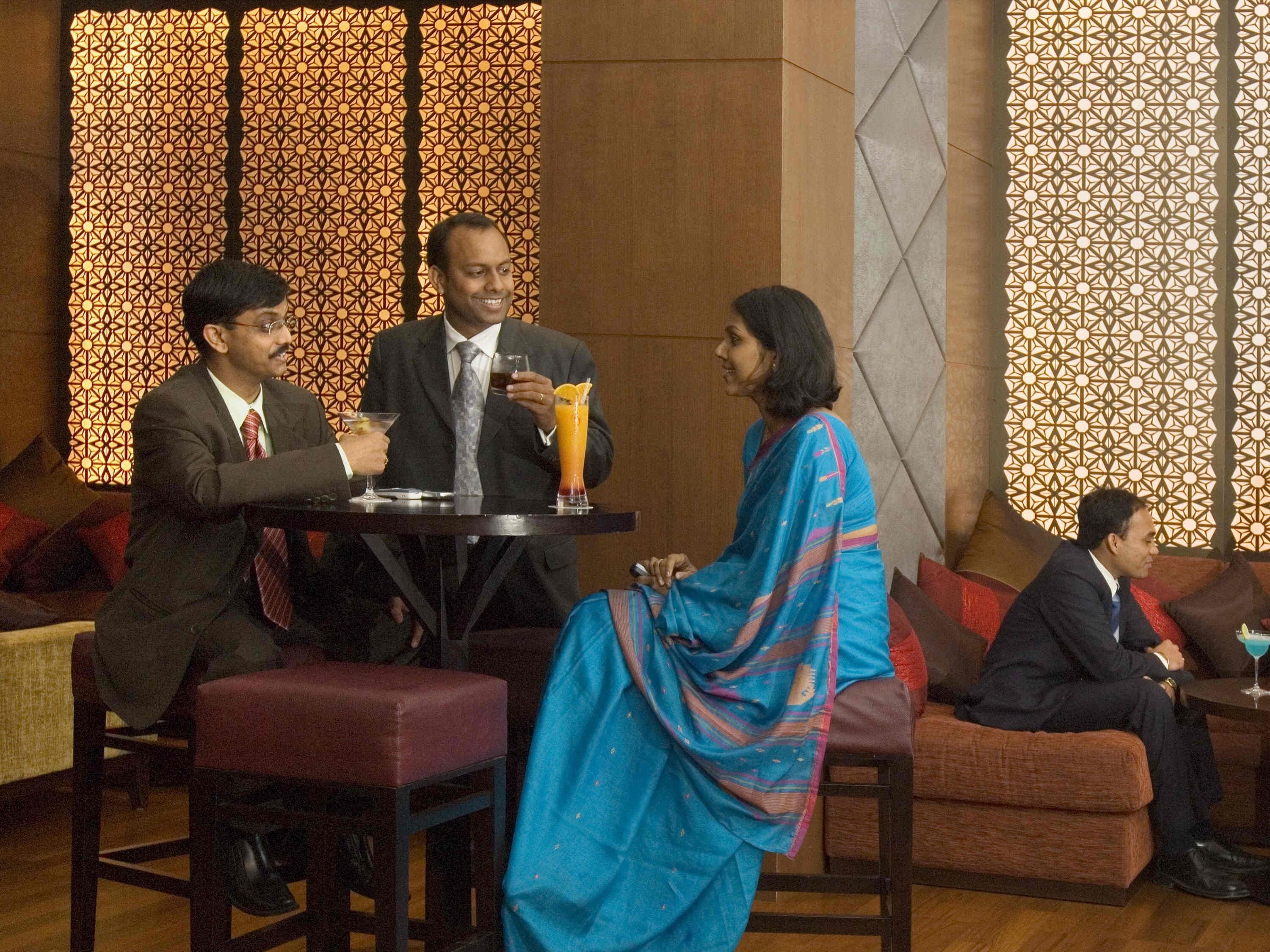 A group of people seated around a table in a room with patterned walls and cushioned seating.