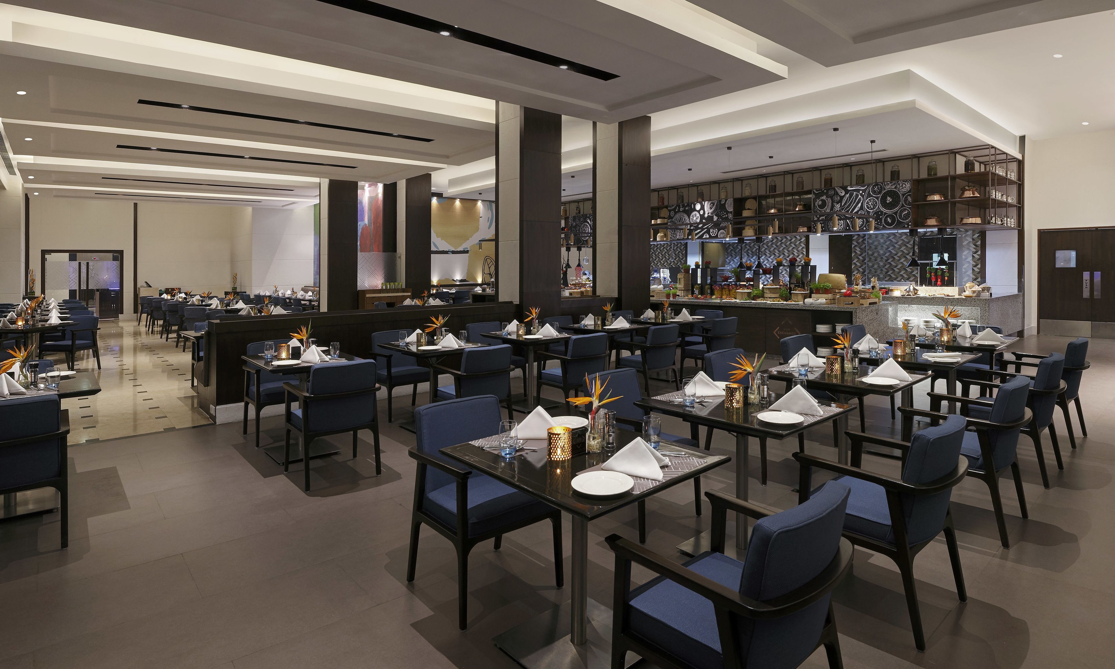 A modern restaurant with tables set for dining, a bar area with a variety of items, and a spacious layout.