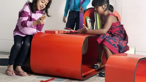 A room with a unique orange cylindrical seating area, a child playing with blocks, and another child sitting at a table with books. - Novotel Hyderabad Convention Centre Hotel (Hyderabad)