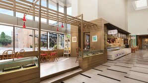Un interior moderno con una zona de estar, una cafetería y vistas a través de amplios ventanales.