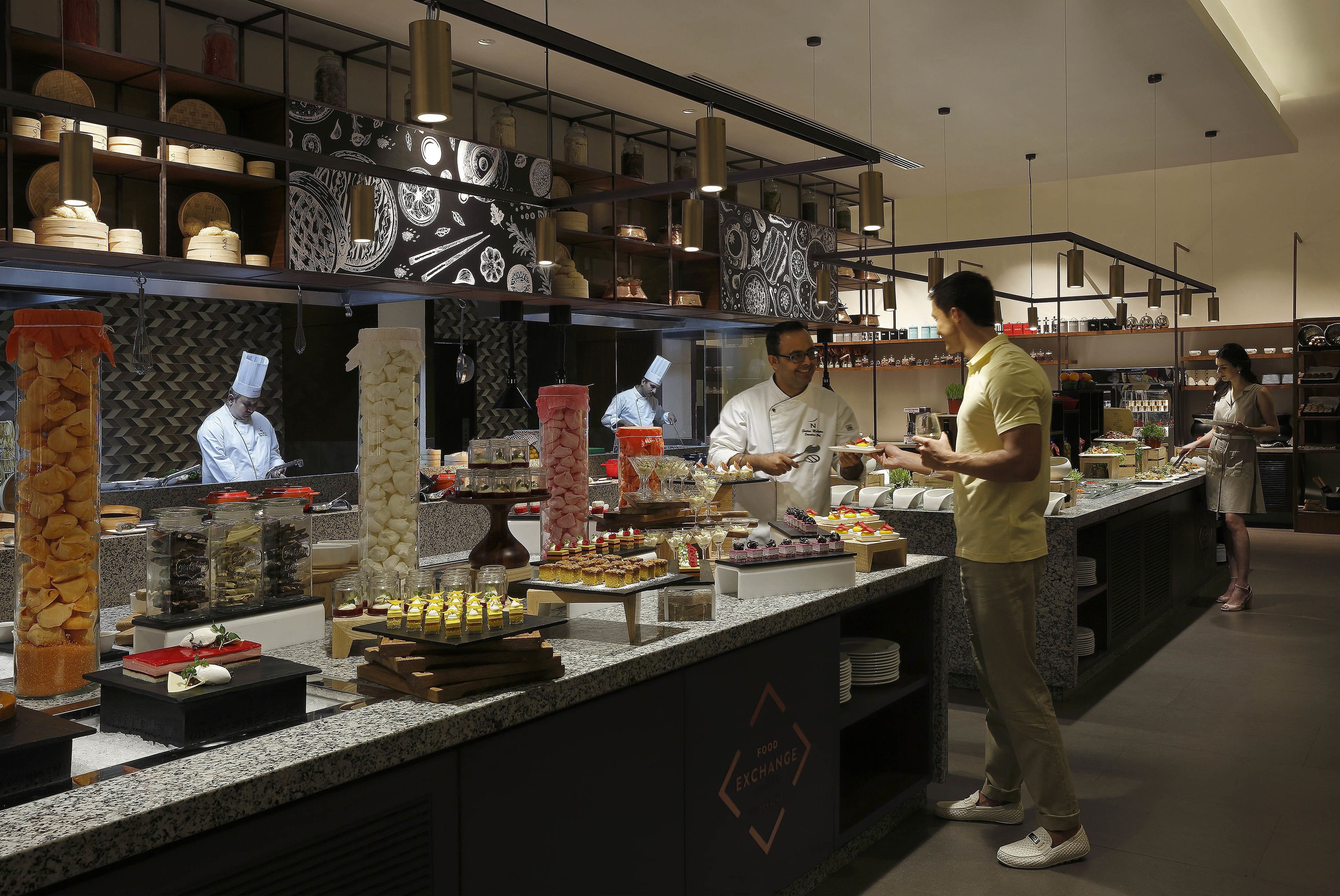A buffet setup with various food items and a chef preparing food.