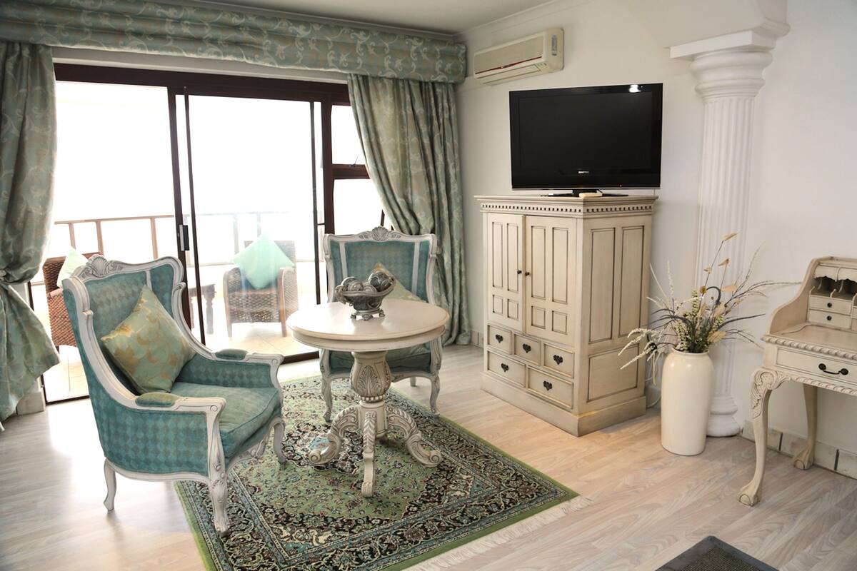Une chambre dotée d’un balcon, d’une télévision, d’une armoire et d’une table décorative.
