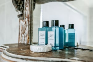 Drei blaue Flaschen KARMA Haarconditioner und Duschgel auf einer Holztischplatte.