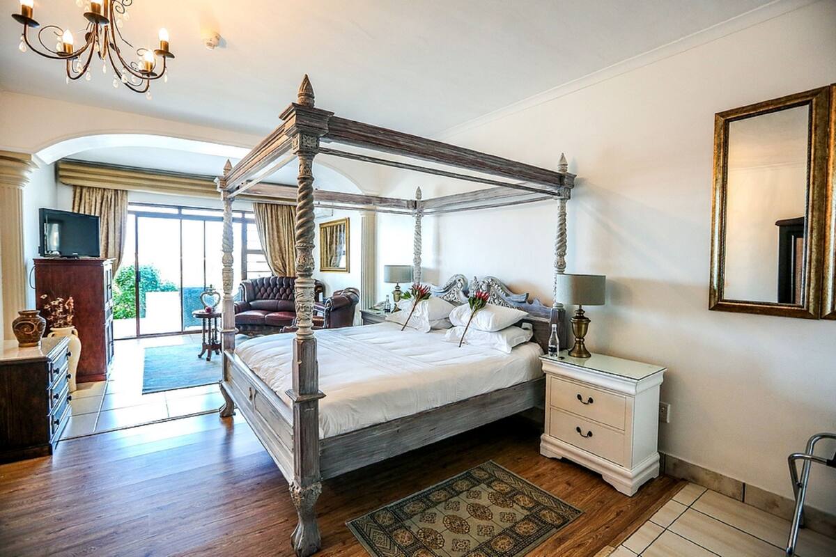 Un lit à baldaquin avec un cadre en bois, une table de chevet avec une lampe et un grand miroir au mur.