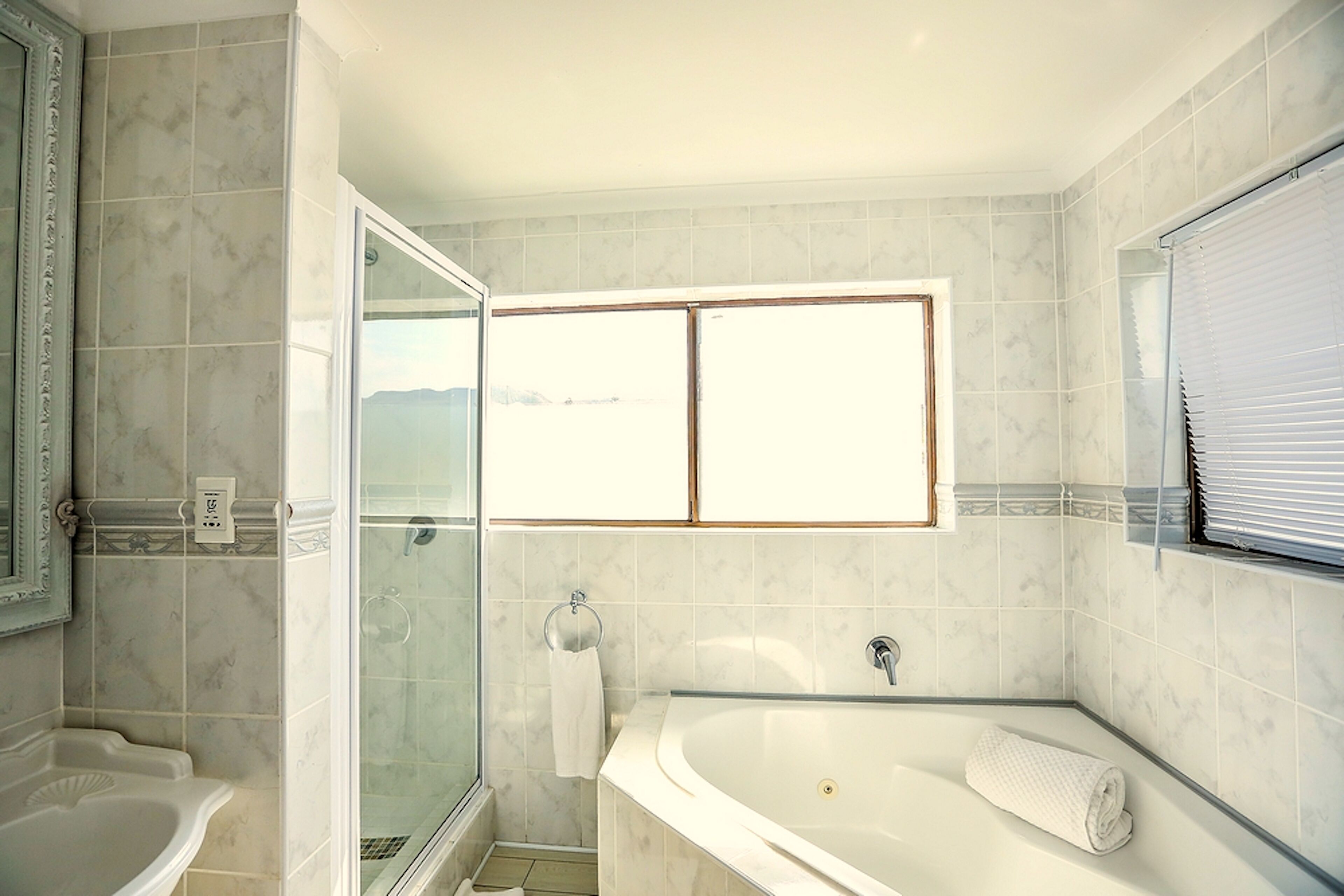 Un baño con bañera, cabina de ducha de vidrio y ventana con vistas.