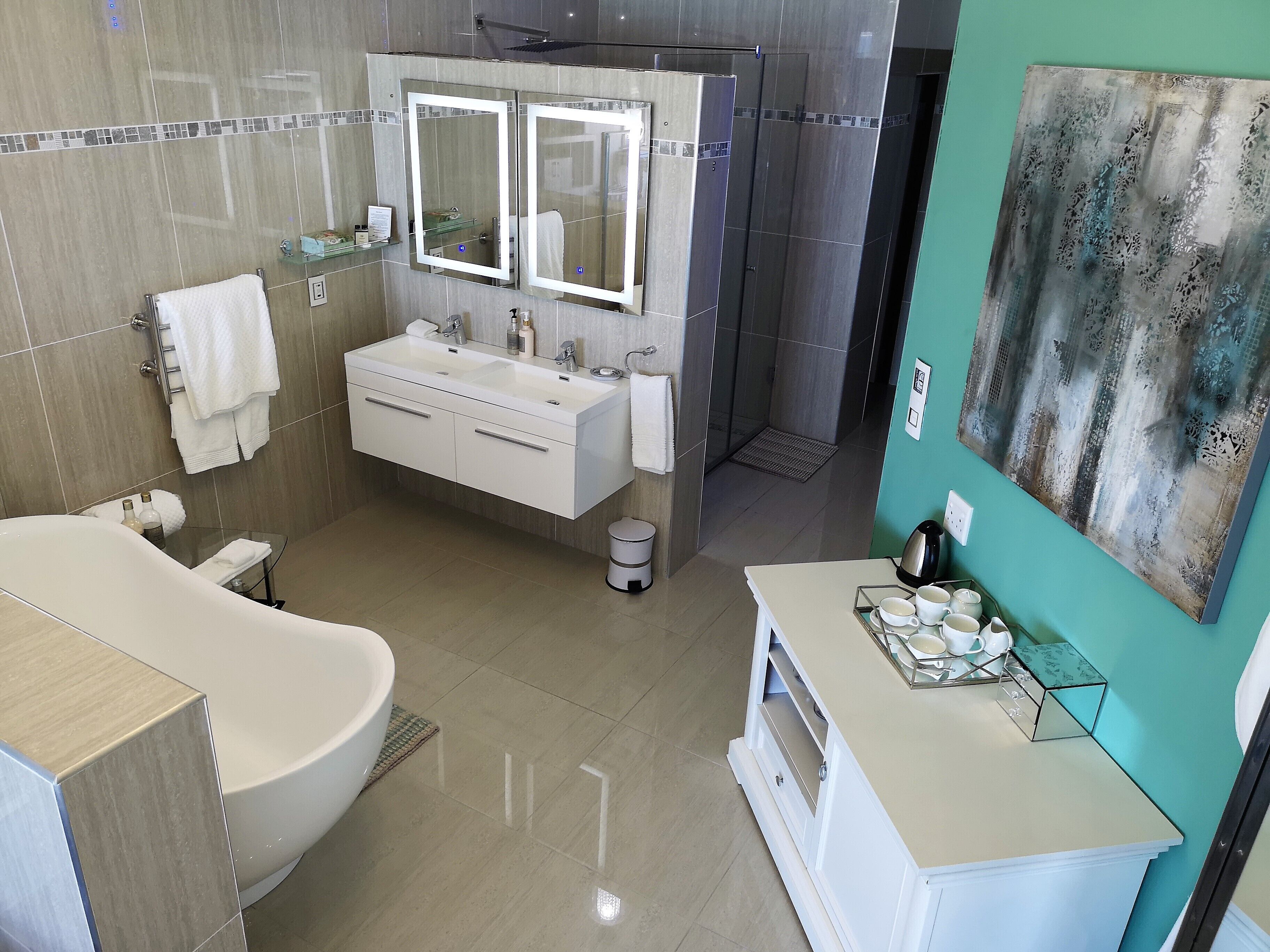A modern bathroom with a freestanding bathtub, a double vanity with a large mirror, and a shower enclosure.