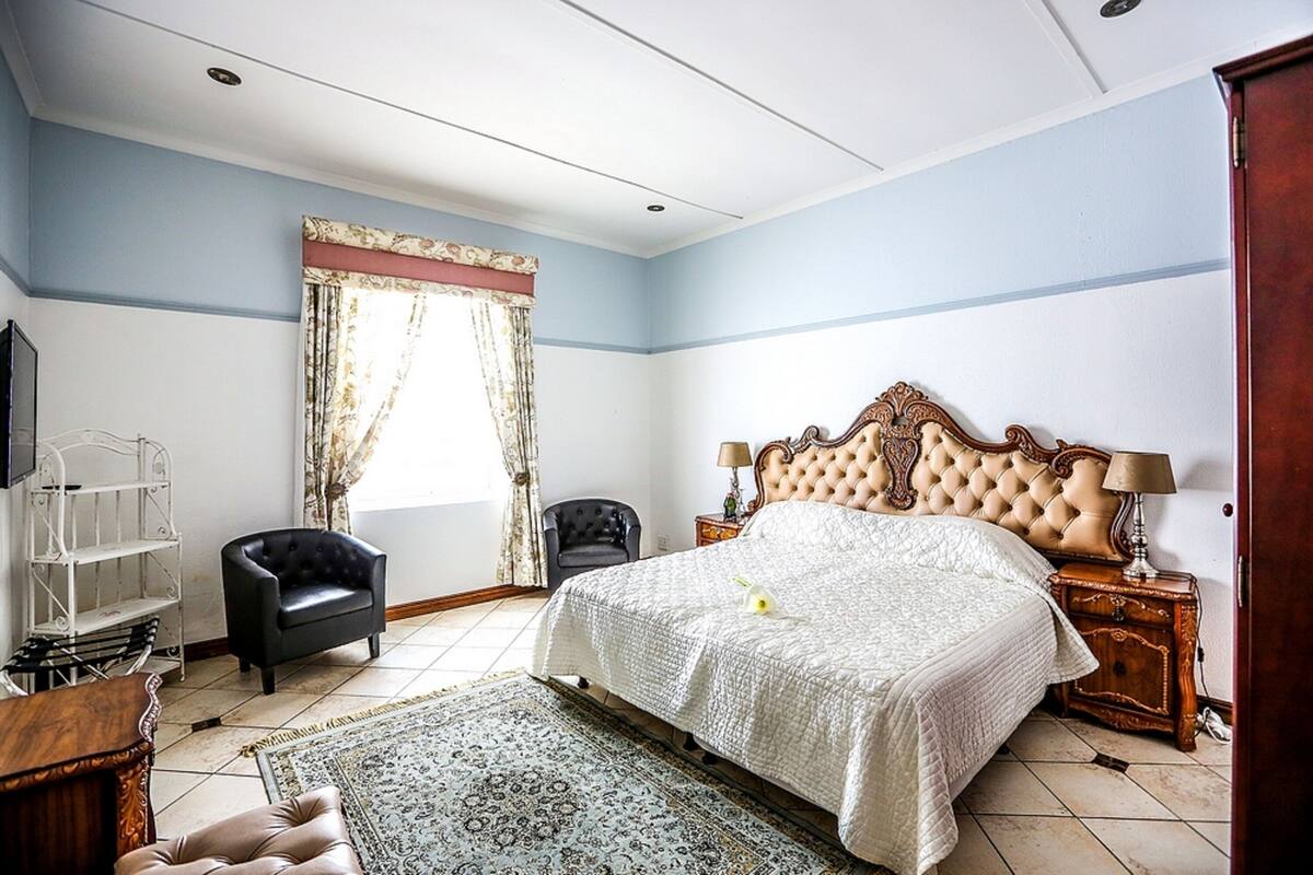 Un dormitorio con una cama grande, una silla, un televisor y una mesita de noche de madera.