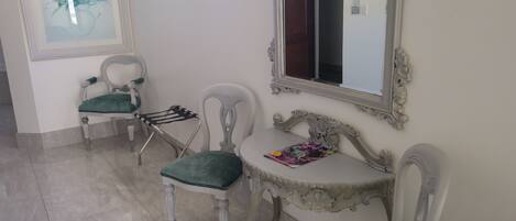 A room with two chairs, a small table, a mirror, and a window.