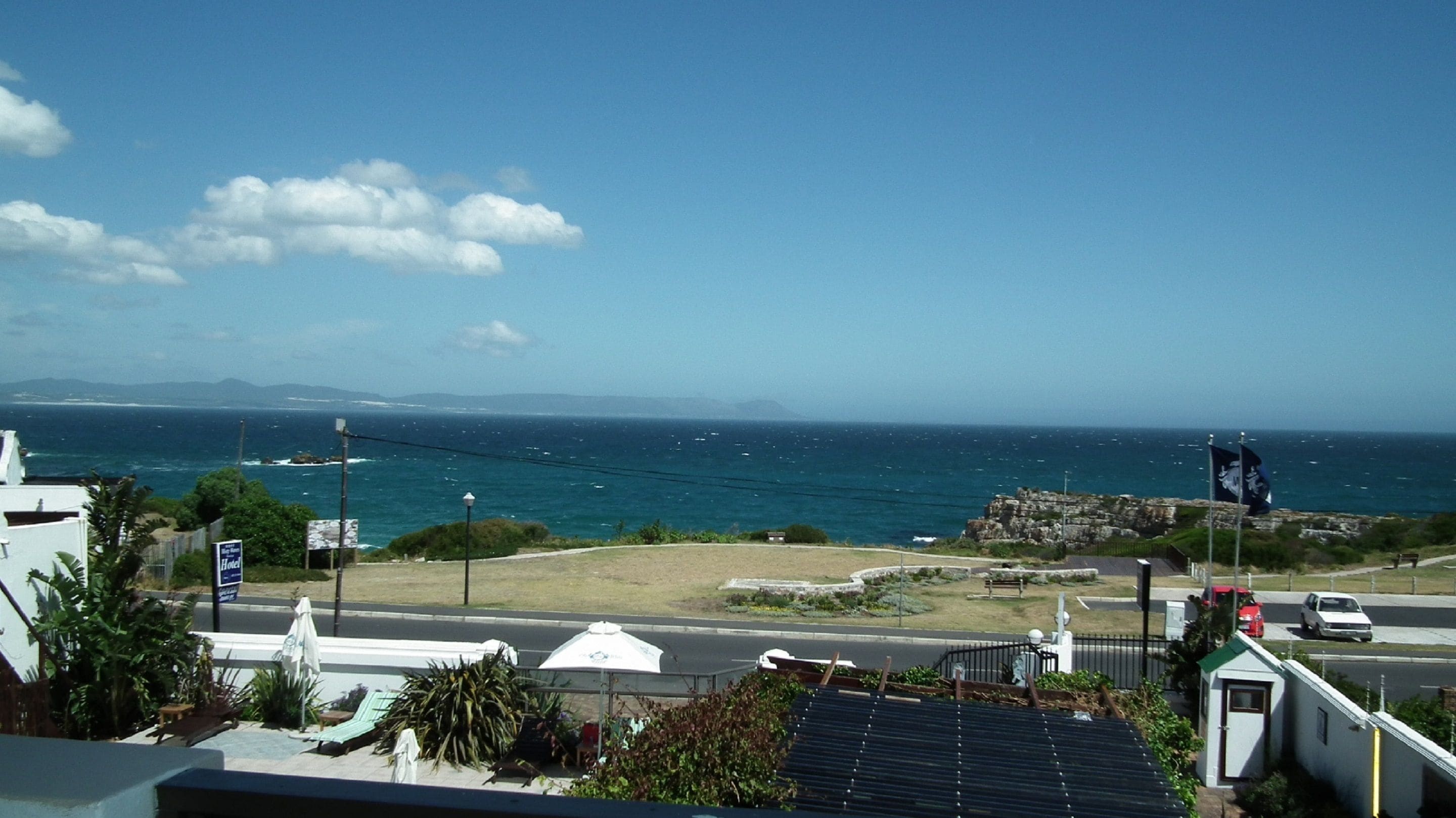 A coastal view with a road, a flag, and a sign for a hotel.
