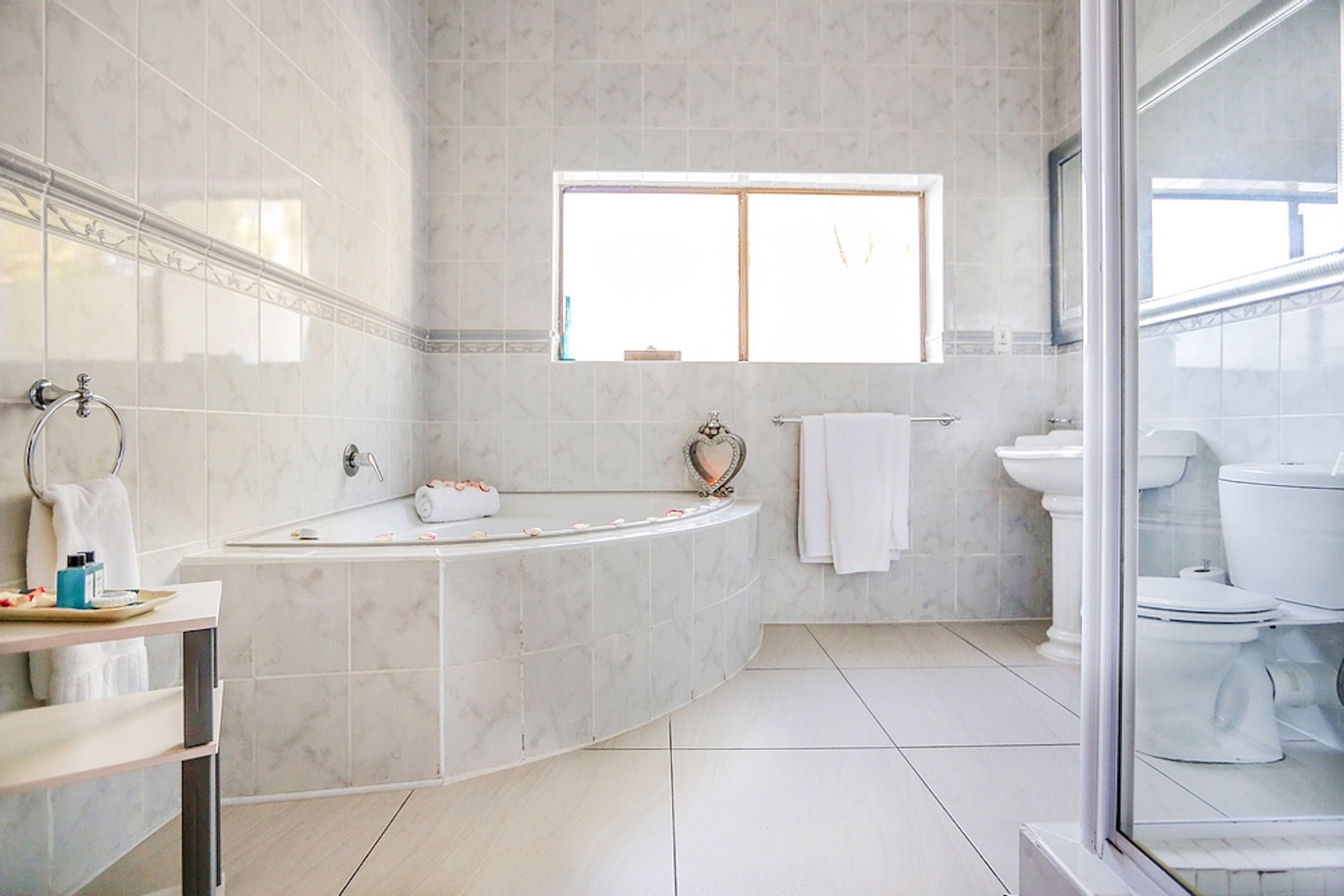 Un baño moderno con una bañera independiente, un espejo grande y un ventanal que proporciona luz natural.