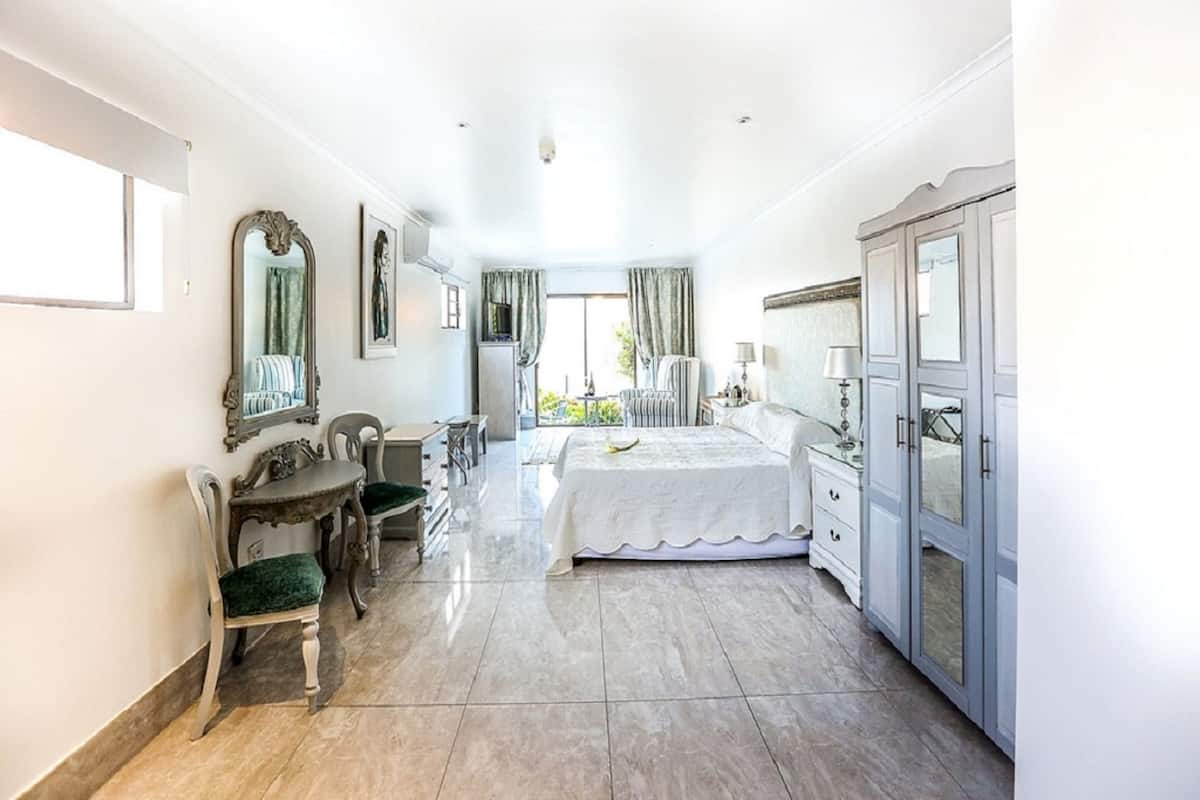 Une chambre spacieuse avec un grand lit, un bureau, une chaise et une armoire.