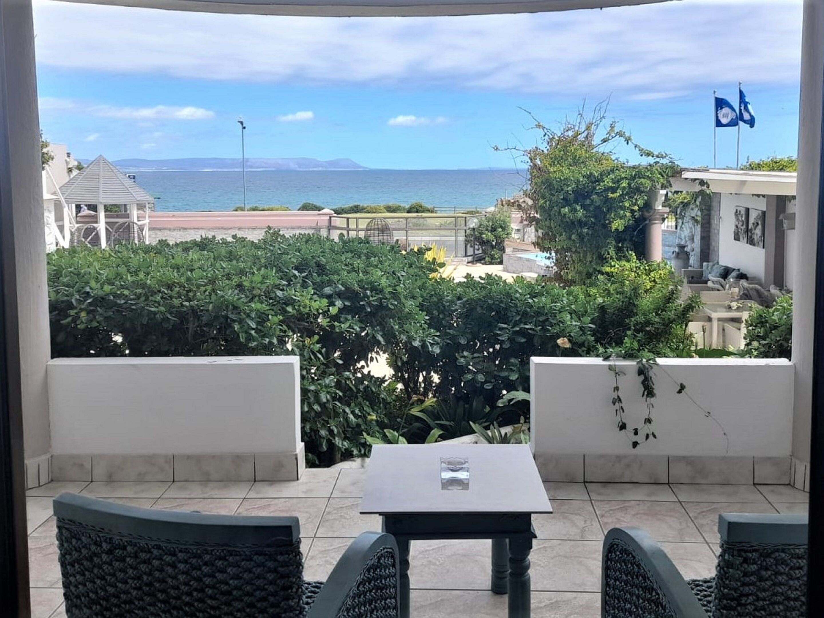 A balcony with a view of the sea, a table, and two chairs.