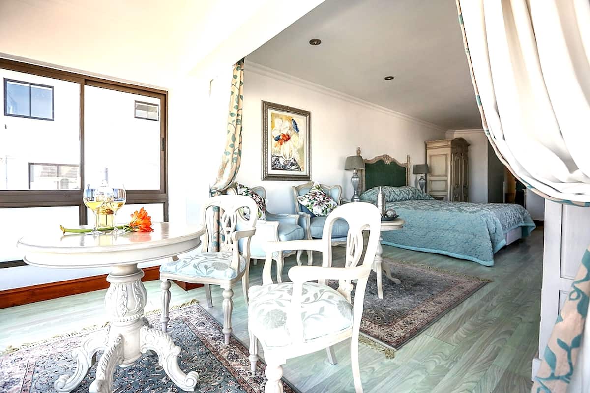 Une chambre à coucher avec un lit, une chaise, une table et un tableau accroché au mur.