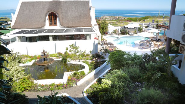A resort with a pool, a fountain, and a view of the ocean. - Misty Waves Boutique Hotel (Hermanus)