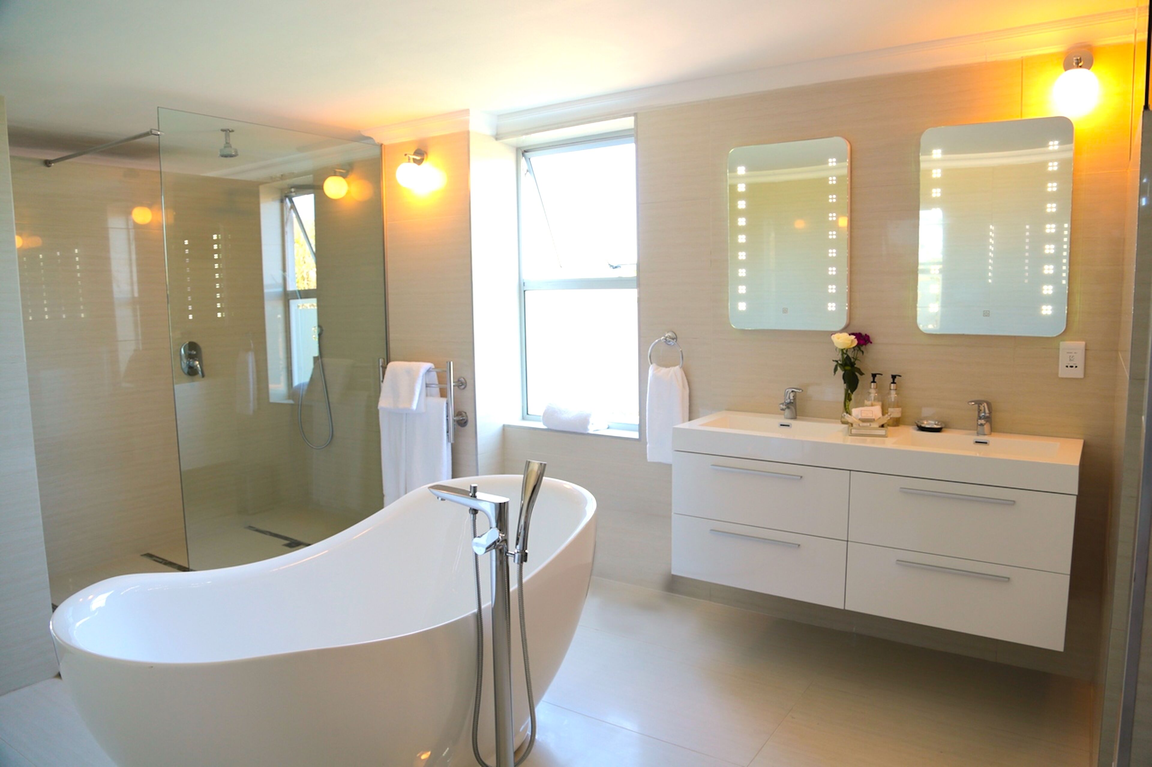 A modern bathroom with a freestanding bathtub, a glass-enclosed shower, and a vanity with a mirror.