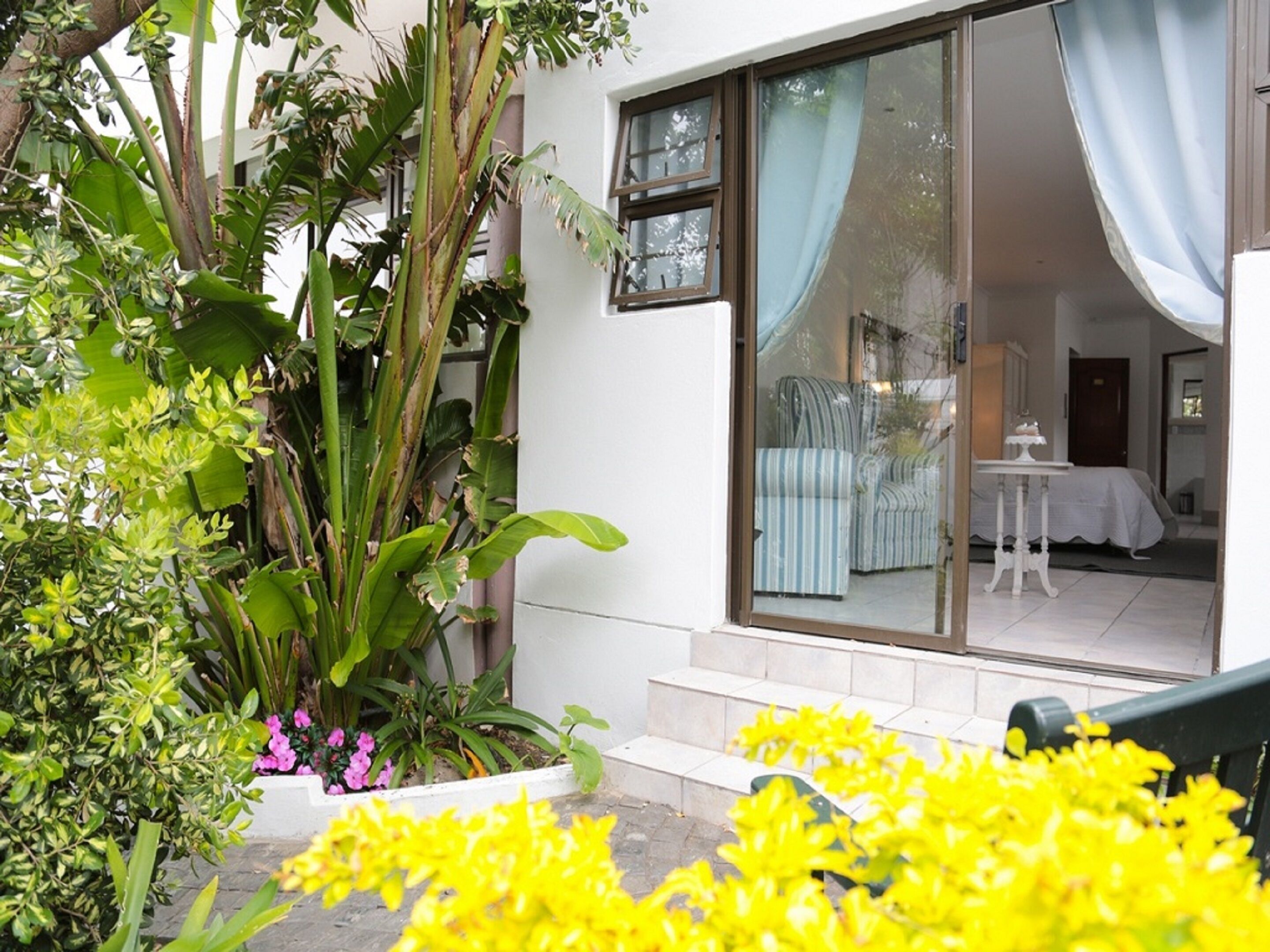 A hotel room with a large sliding glass door, a bed, a small table, and a chair.