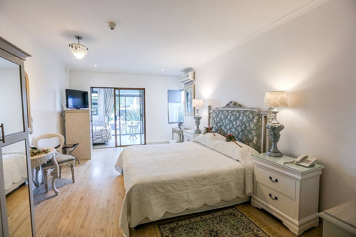 Une chambre à coucher avec un lit, des tables de chevet, une télévision et une vue sur l’extérieur.