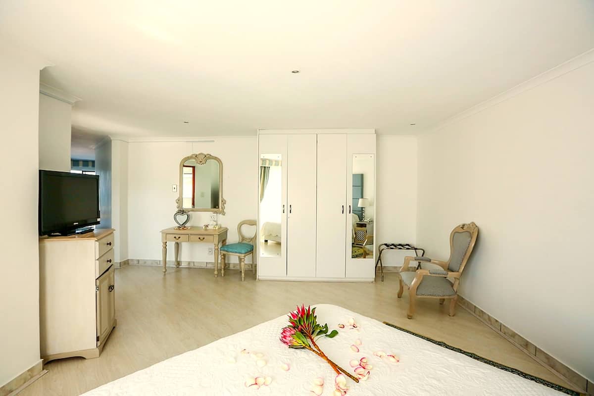 Une chambre à coucher comprenant un lit, une télévision, une commode, une coiffeuse, une chaise et une armoire.