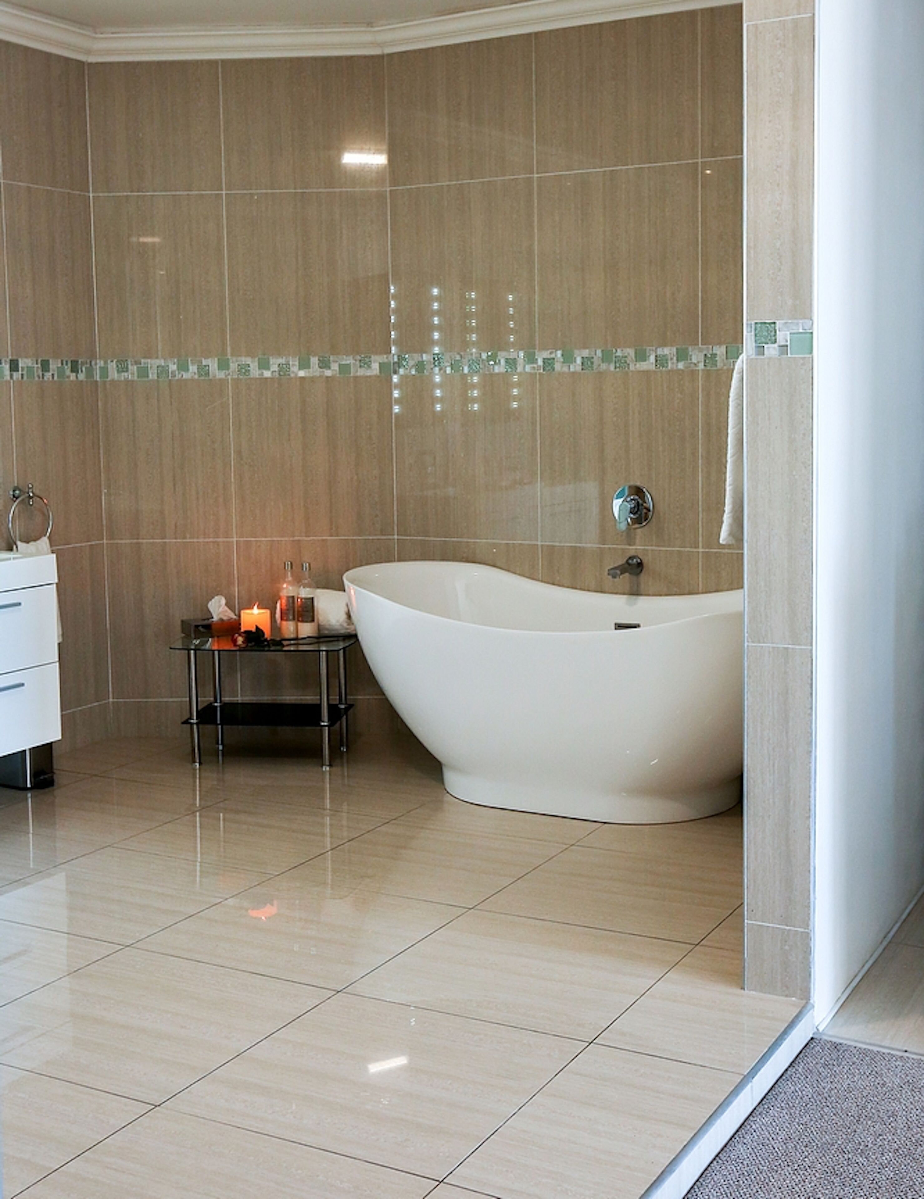 A modern bathroom with a freestanding bathtub, a vanity with a mirror, and a small table with candles.