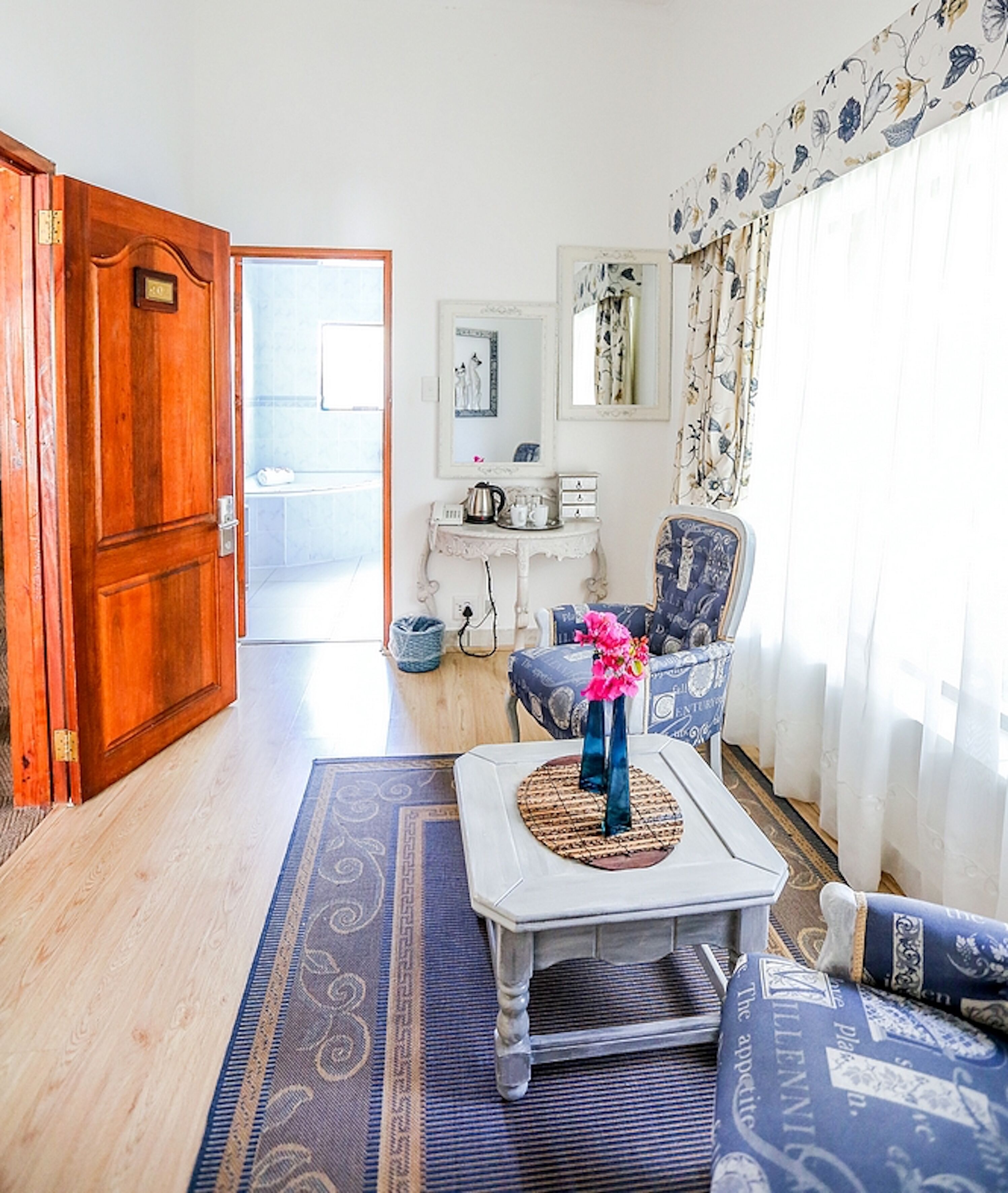 Un soggiorno con una porta in legno, un divano, un tavolino da caffè e vista sul bagno.