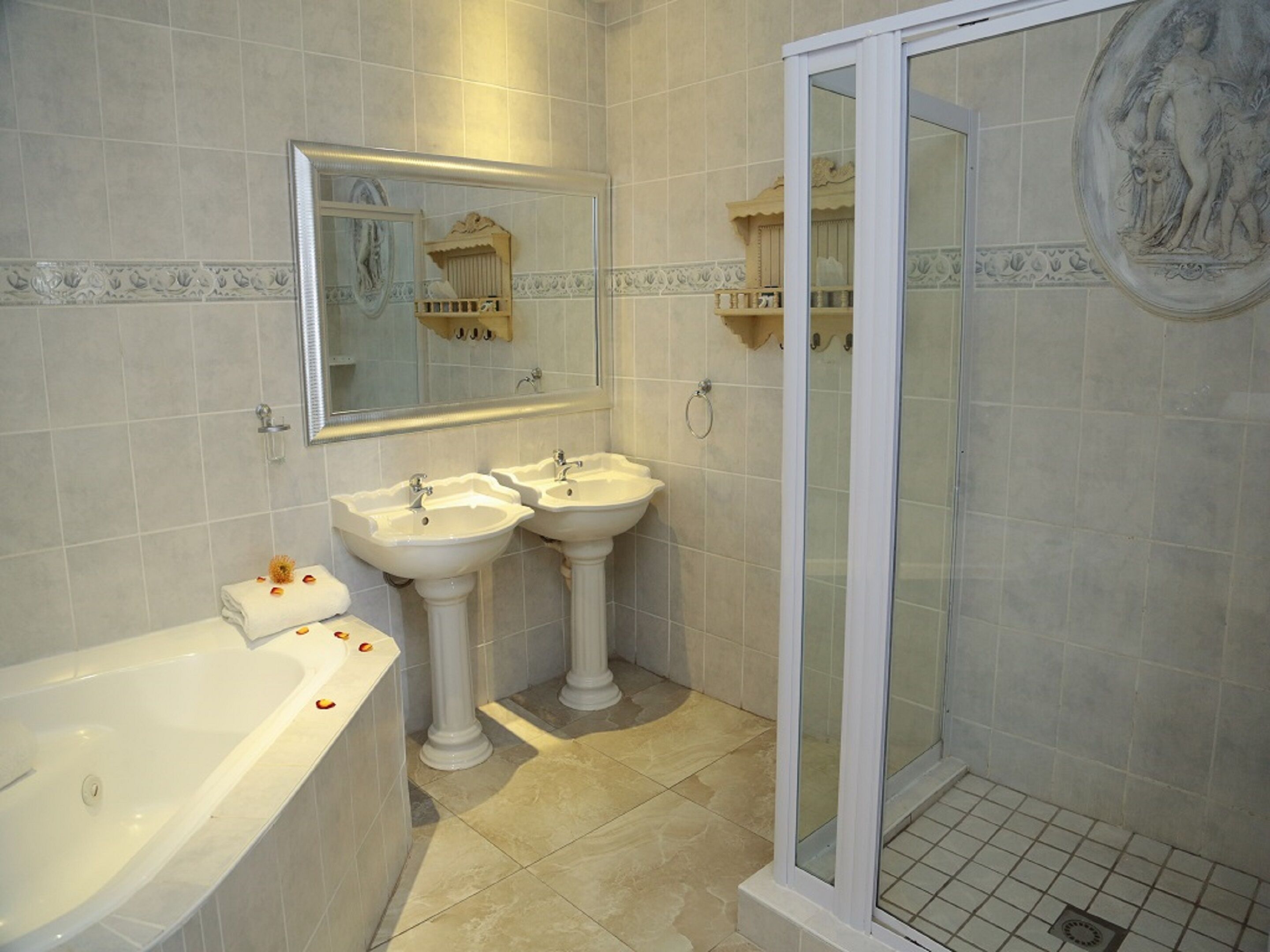 A bathroom with two sinks, a bathtub, and a glass-enclosed shower.
